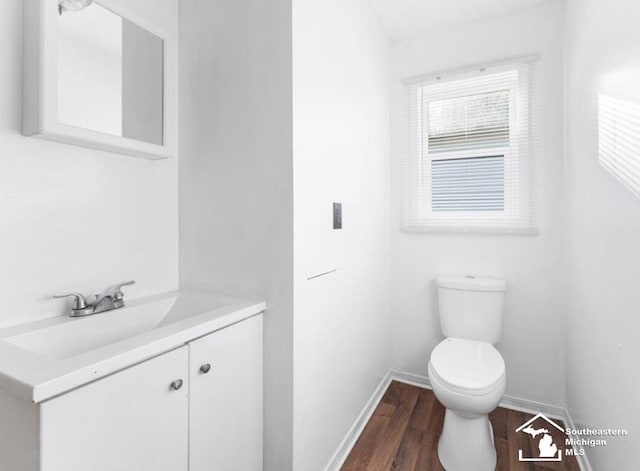 bathroom with toilet, baseboards, wood finished floors, and vanity