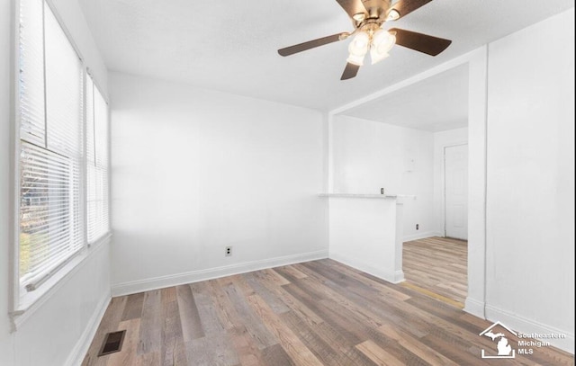 spare room featuring a ceiling fan, baseboards, visible vents, and wood finished floors