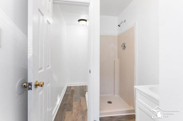 full bath featuring a stall shower, vanity, and wood finished floors