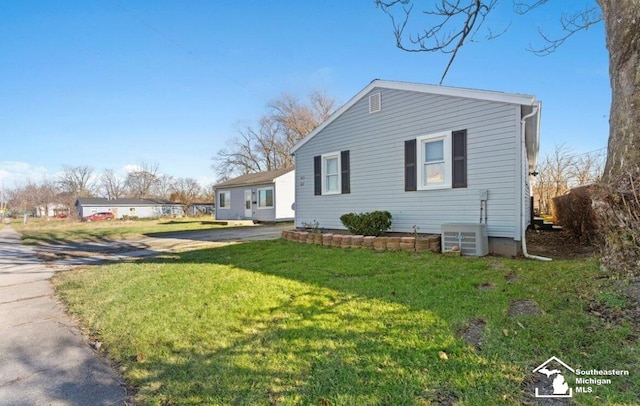 view of side of property featuring cooling unit and a yard