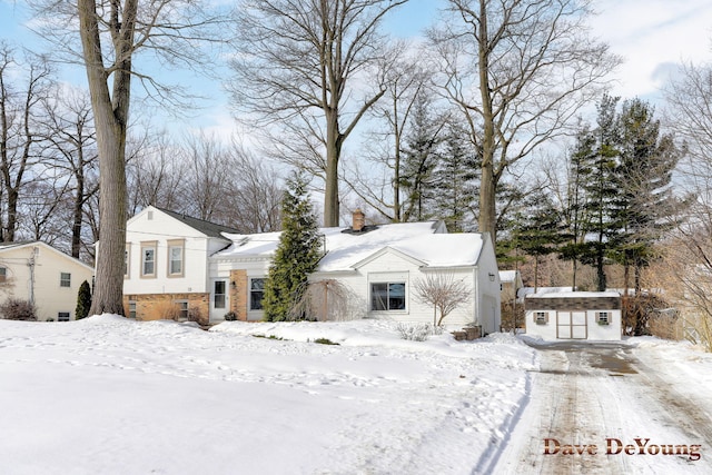 view of front facade featuring a garage, a chimney, and an outdoor structure