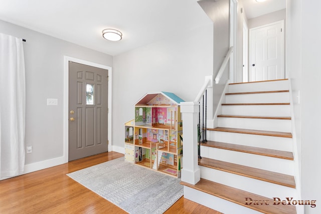 foyer entrance with stairway, wood finished floors, and baseboards