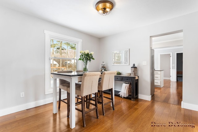 dining space with baseboards and wood finished floors