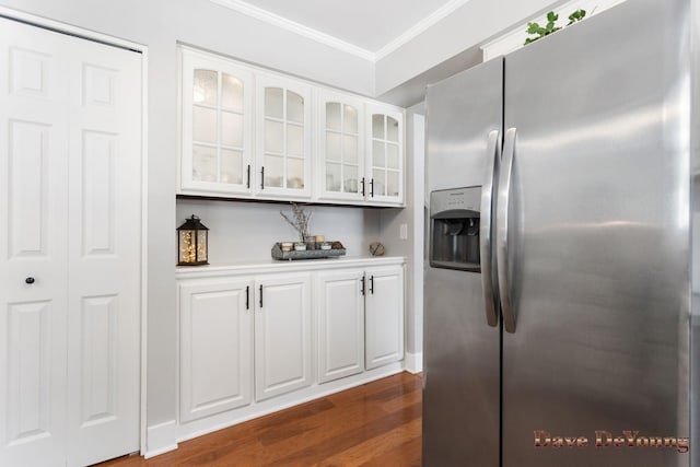 kitchen featuring light countertops, glass insert cabinets, ornamental molding, white cabinets, and stainless steel fridge with ice dispenser