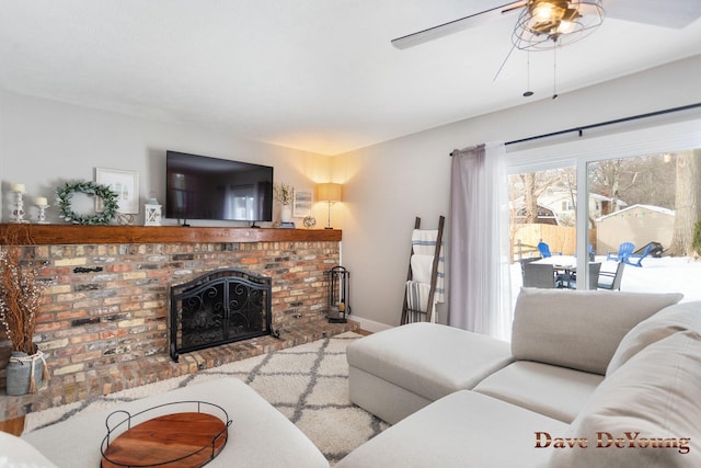 living room with ceiling fan, a brick fireplace, and baseboards