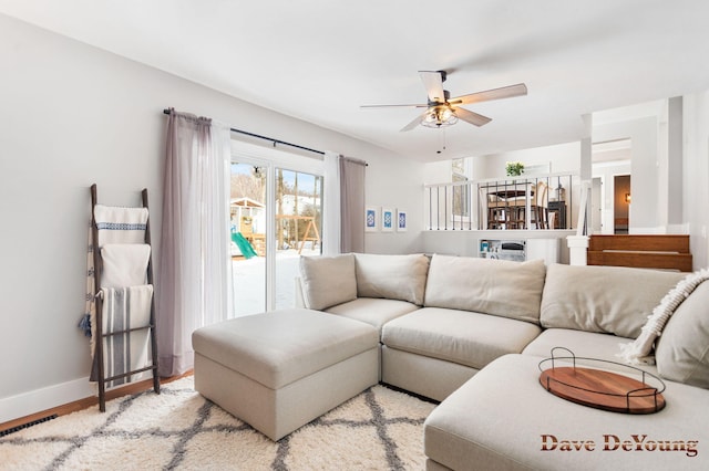 living room with visible vents, light wood finished floors, a ceiling fan, and baseboards