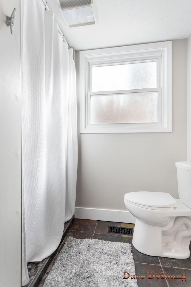 full bath featuring toilet, plenty of natural light, visible vents, and baseboards