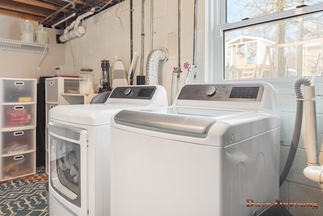 clothes washing area featuring laundry area, concrete block wall, and washer and dryer