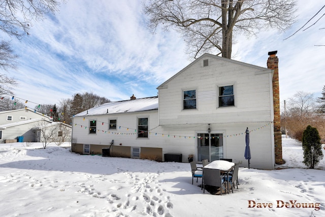 snow covered property with a garage and a chimney