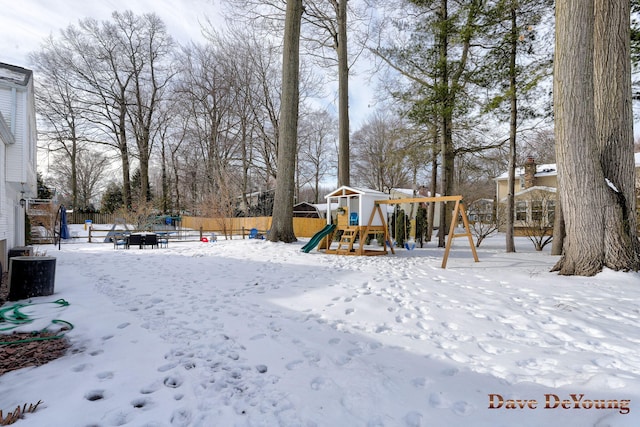 yard covered in snow featuring a playground and fence