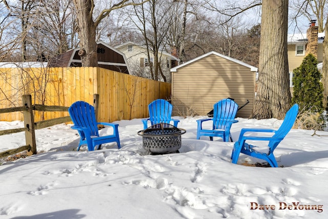 snow covered patio with fence and a fire pit