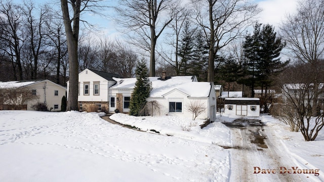 view of front of home with a garage, stone siding, an outdoor structure, and a chimney