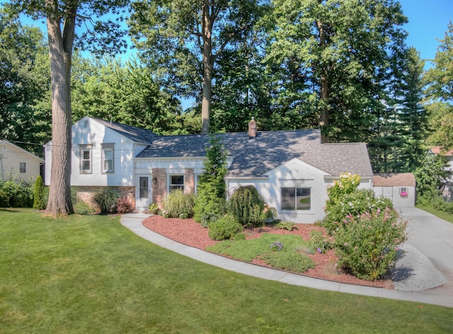 tri-level home featuring concrete driveway, a chimney, roof with shingles, a front lawn, and brick siding