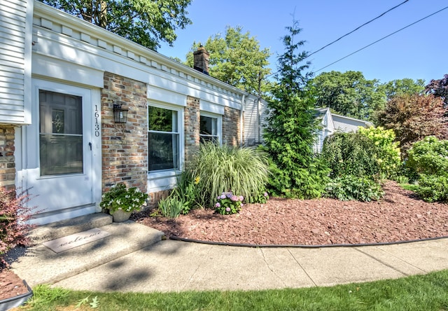 exterior space featuring stone siding, brick siding, and a chimney