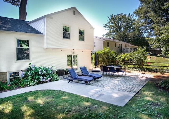 rear view of property with a shingled roof, a yard, and fence