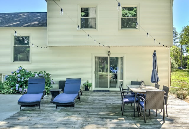 exterior space featuring roof with shingles, outdoor dining area, and a wooden deck