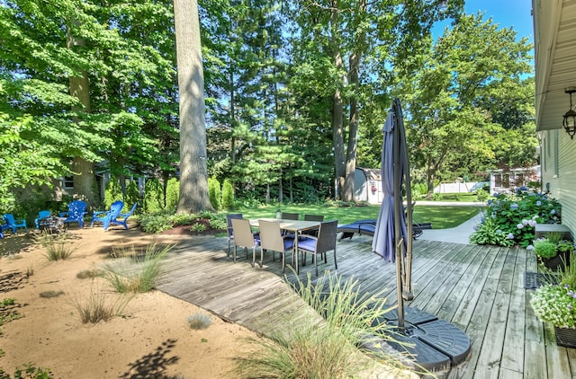 wooden terrace with outdoor dining space, an outdoor structure, and a shed