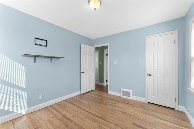 unfurnished bedroom featuring light wood finished floors, visible vents, and baseboards