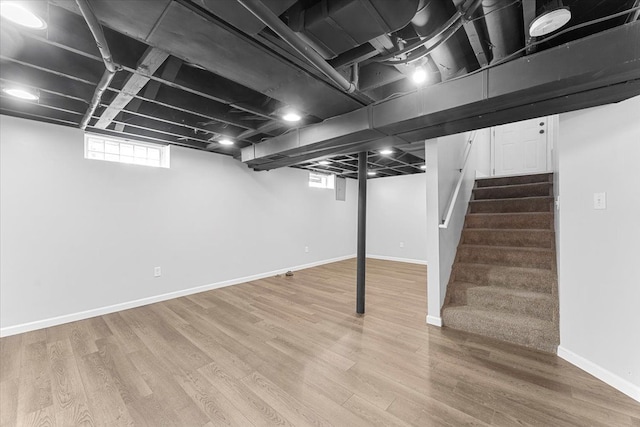 below grade area featuring stairway, wood finished floors, and baseboards