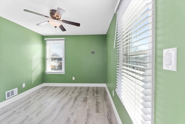 empty room with ceiling fan, light wood-type flooring, visible vents, and baseboards