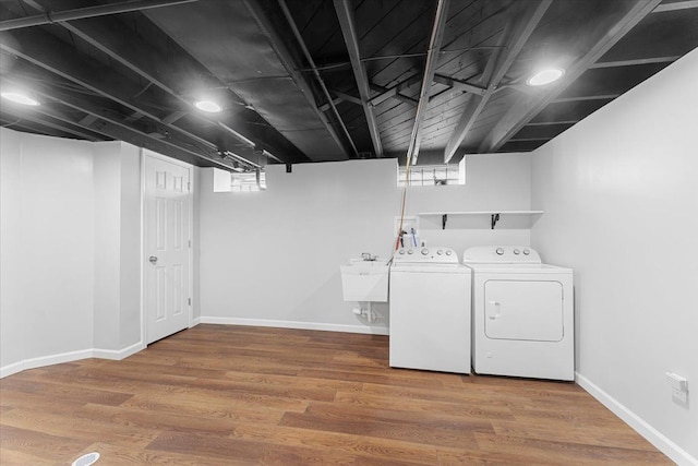 laundry area featuring laundry area, washing machine and dryer, a sink, and wood finished floors