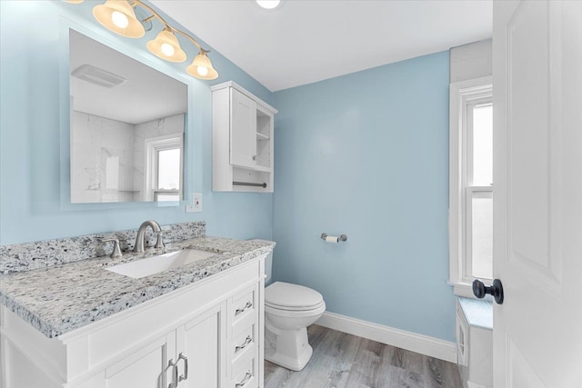 bathroom with visible vents, baseboards, toilet, wood finished floors, and vanity