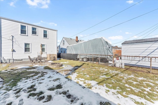 snow covered rear of property featuring an outdoor fire pit and fence