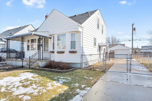 bungalow with an outbuilding, a detached garage, concrete driveway, a gate, and fence