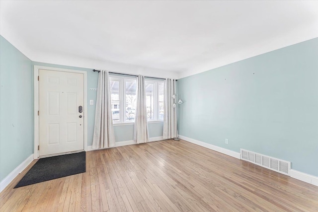 foyer with light wood-type flooring, visible vents, and baseboards