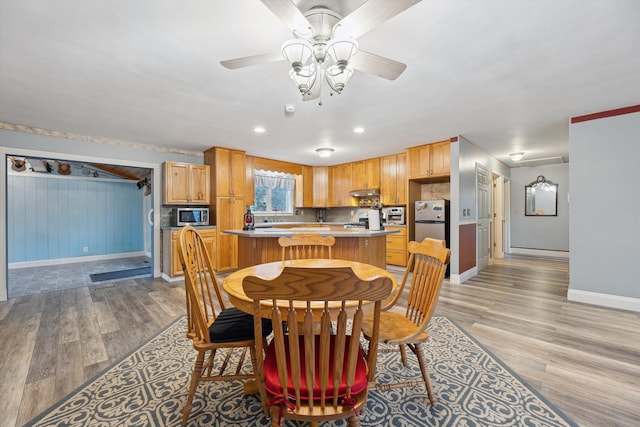 dining room with a ceiling fan, light wood-style flooring, and baseboards