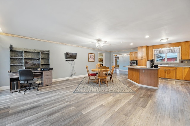 kitchen with a center island, light countertops, light wood-style flooring, and baseboards