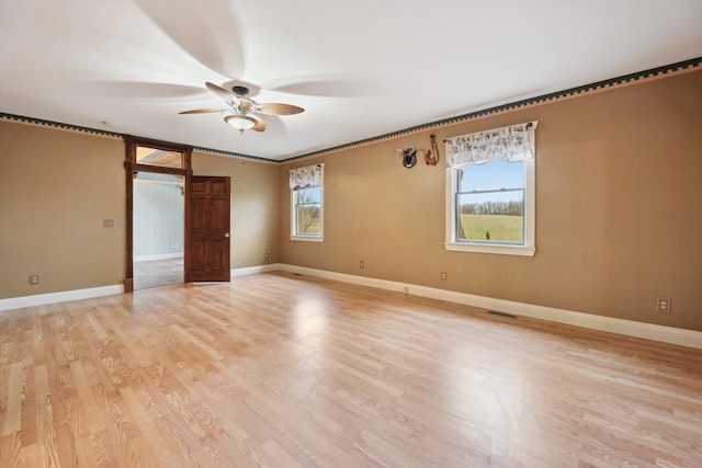 unfurnished room with light wood-style floors, visible vents, ceiling fan, and baseboards