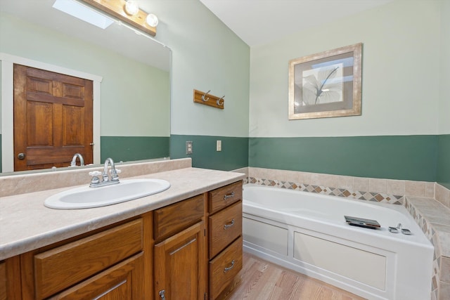 full bathroom with a skylight, a bath, and vanity