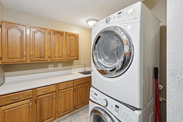 washroom featuring cabinet space, a sink, stacked washing maching and dryer, and light tile patterned floors