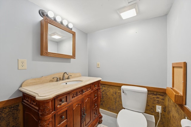 bathroom with wainscoting, vanity, and toilet