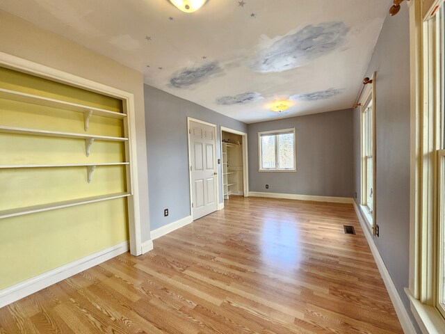 unfurnished bedroom featuring light wood finished floors, visible vents, and baseboards