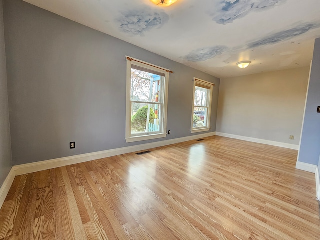 spare room with light wood-style floors, visible vents, and baseboards