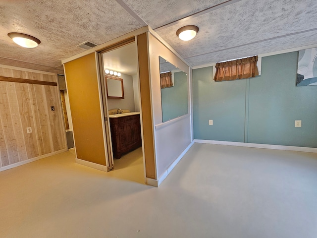 interior space featuring visible vents, wood walls, a sink, and baseboards