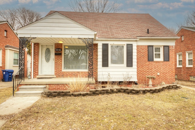 bungalow with a porch, brick siding, and a shingled roof