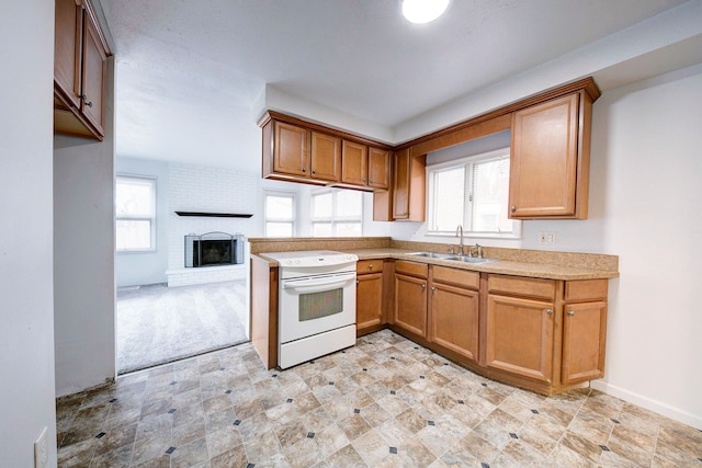 kitchen featuring white electric stove, a brick fireplace, a sink, and a wealth of natural light