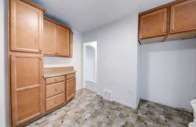 kitchen featuring light countertops, brown cabinets, visible vents, and baseboards