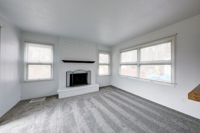 unfurnished living room with carpet floors, a brick fireplace, and visible vents