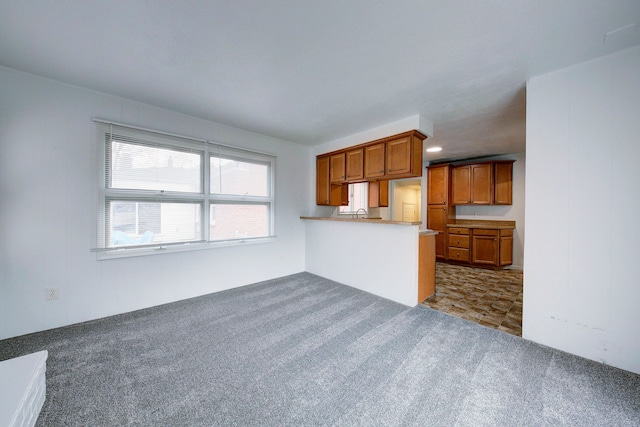 kitchen featuring brown cabinetry, dark colored carpet, and a peninsula