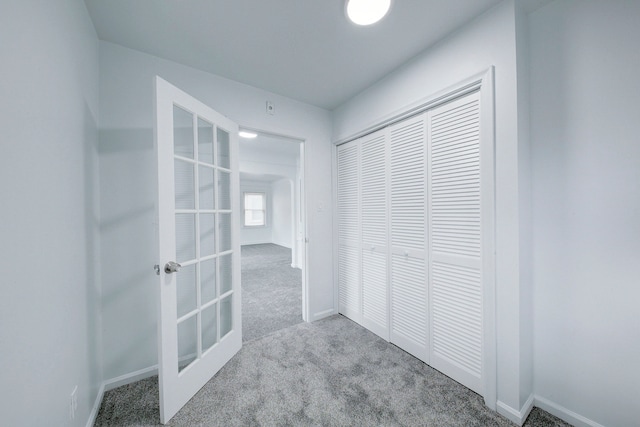 hall with carpet floors, french doors, and baseboards