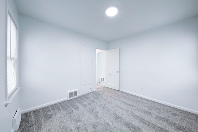 spare room with carpet flooring, visible vents, and baseboards