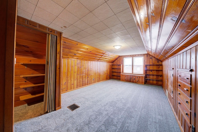 additional living space with lofted ceiling, carpet floors, wood walls, and visible vents