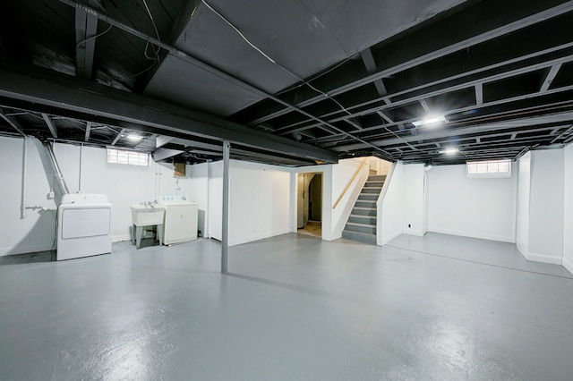 basement featuring stairs, baseboards, a sink, and washer and dryer