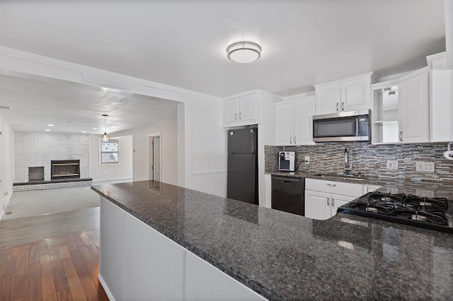 kitchen featuring dark wood-style flooring, black appliances, a fireplace, white cabinetry, and a sink