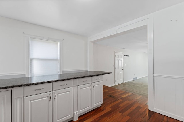 kitchen with dark stone counters, dark wood finished floors, and white cabinets