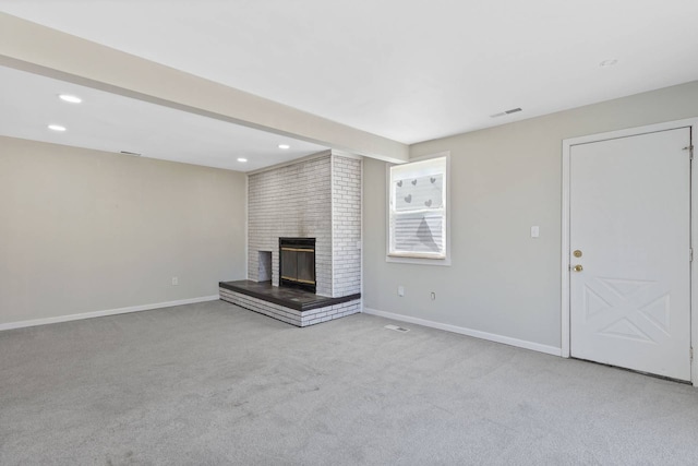 unfurnished living room with a brick fireplace, carpet flooring, visible vents, and baseboards